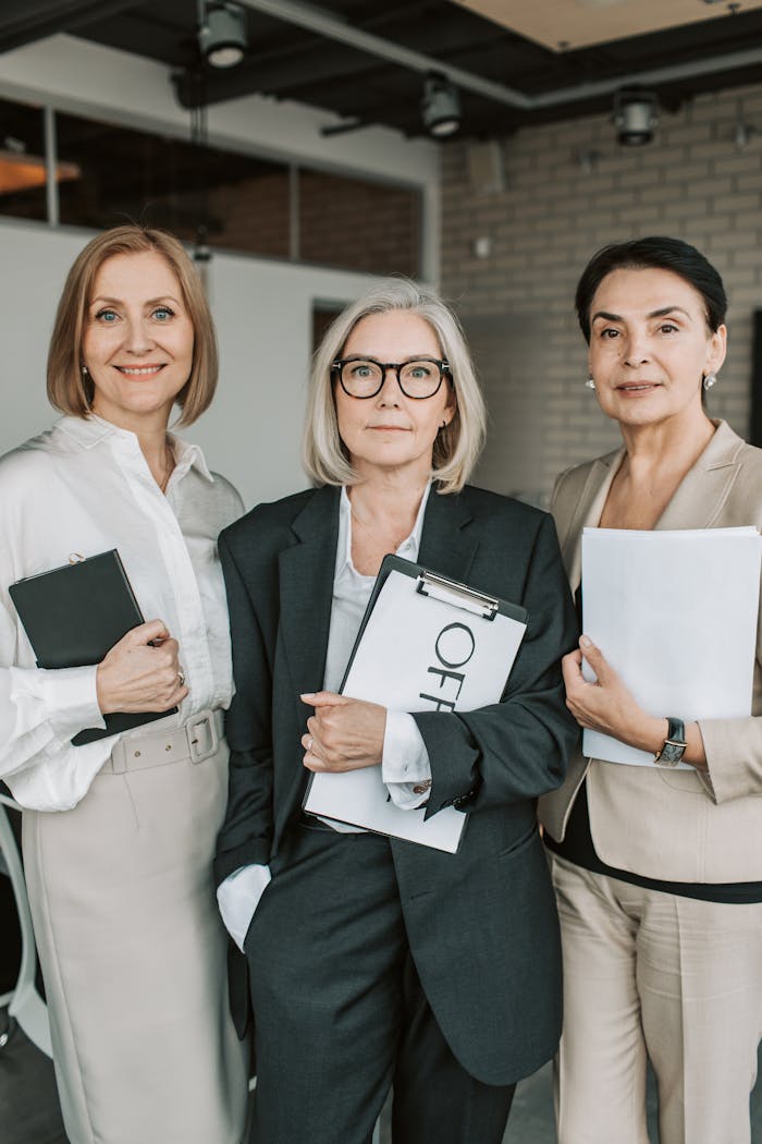 Group of senior female professionals confidently posing in office setting.